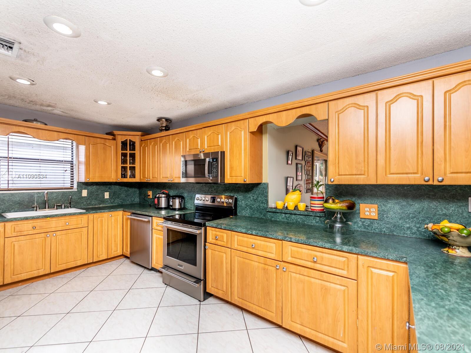 2820 Southwest 95th Avenue Miami, FL 33165 - Photo 31 of 100 a kitchen with stainless steel appliances granite countertop a stove top oven a sink a dining table and chairs