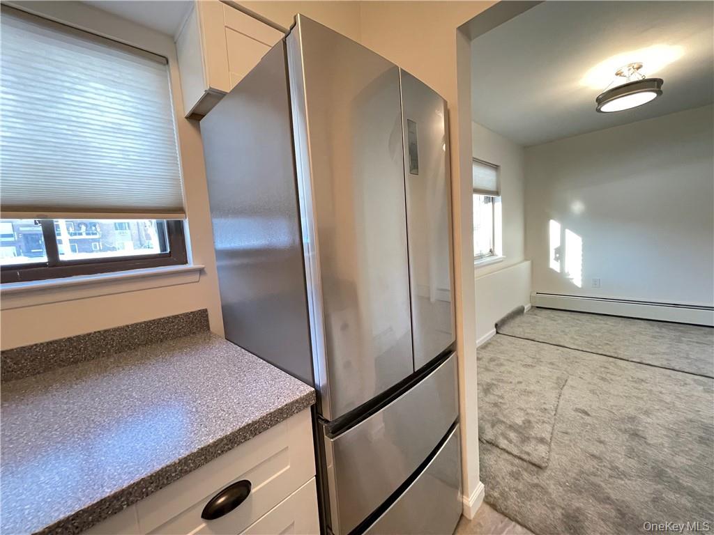 27 Tanager Road, Unit 2702 Monroe, NY 10950 - Photo 4 of 17 Stainless steel French door refrigerator with bottom freezer drawers, complemented by white cabinetry and a speckled countertop