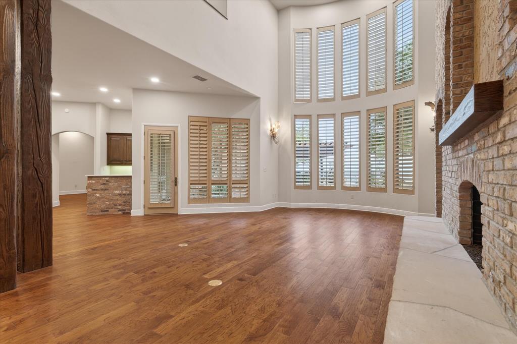 701 West Walcott Street Pilot Point, TX 76258 - Photo 15 of 40 Unfurnished living room with a brick fireplace, light wood-type flooring, arched walkways, a high ceiling, and recessed lighting
