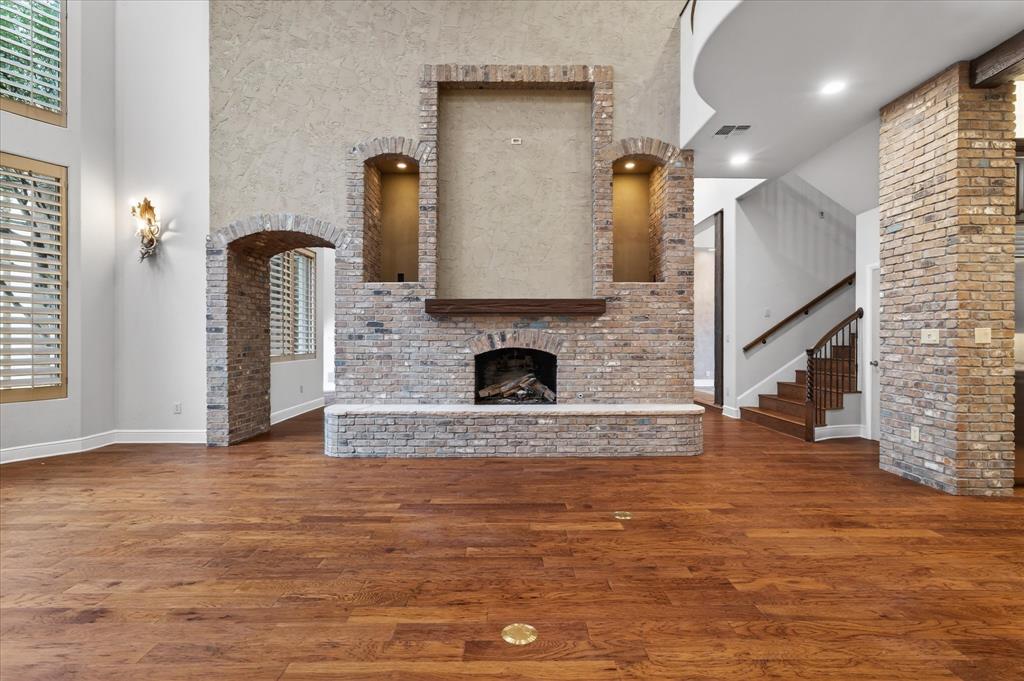 701 West Walcott Street Pilot Point, TX 76258 - Photo 16 of 40 Unfurnished living room with wood finished floors, a fireplace, a high ceiling, arched walkways, and recessed lighting