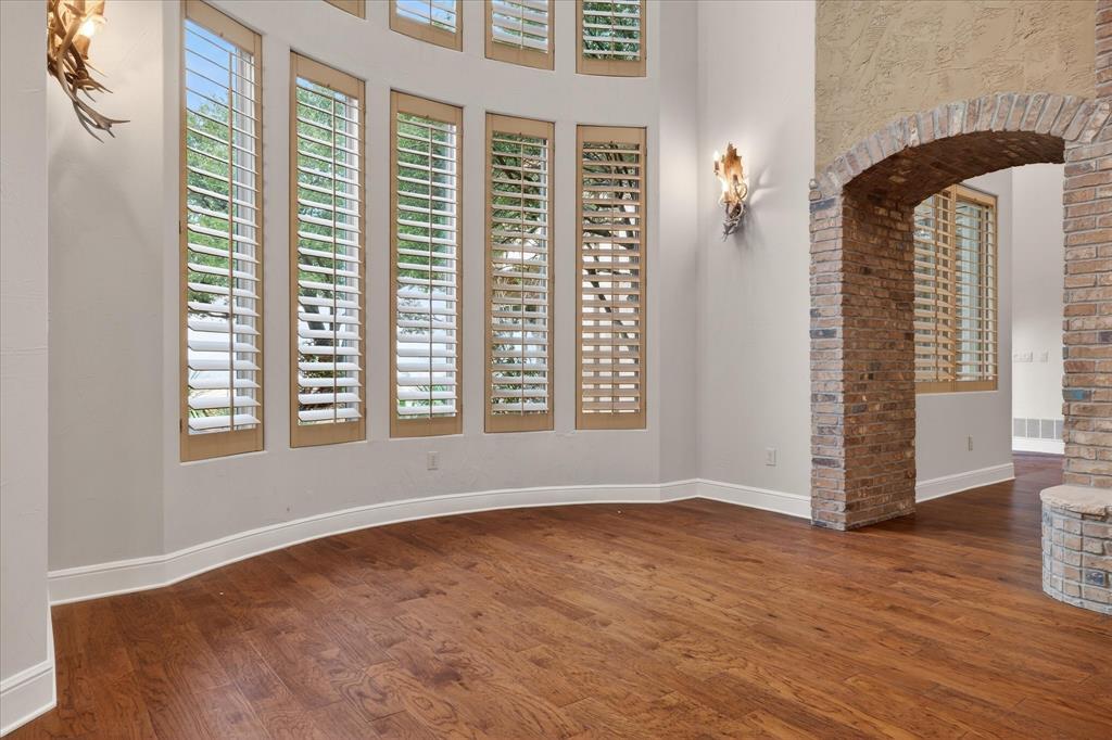 701 West Walcott Street Pilot Point, TX 76258 - Photo 17 of 40 Spare room featuring arched walkways, dark wood finished floors, plenty of natural light, and a high ceiling