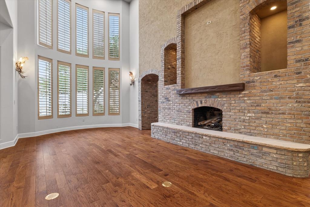 701 West Walcott Street Pilot Point, TX 76258 - Photo 20 of 40 Unfurnished living room featuring a fireplace, dark wood finished floors, and a high ceiling