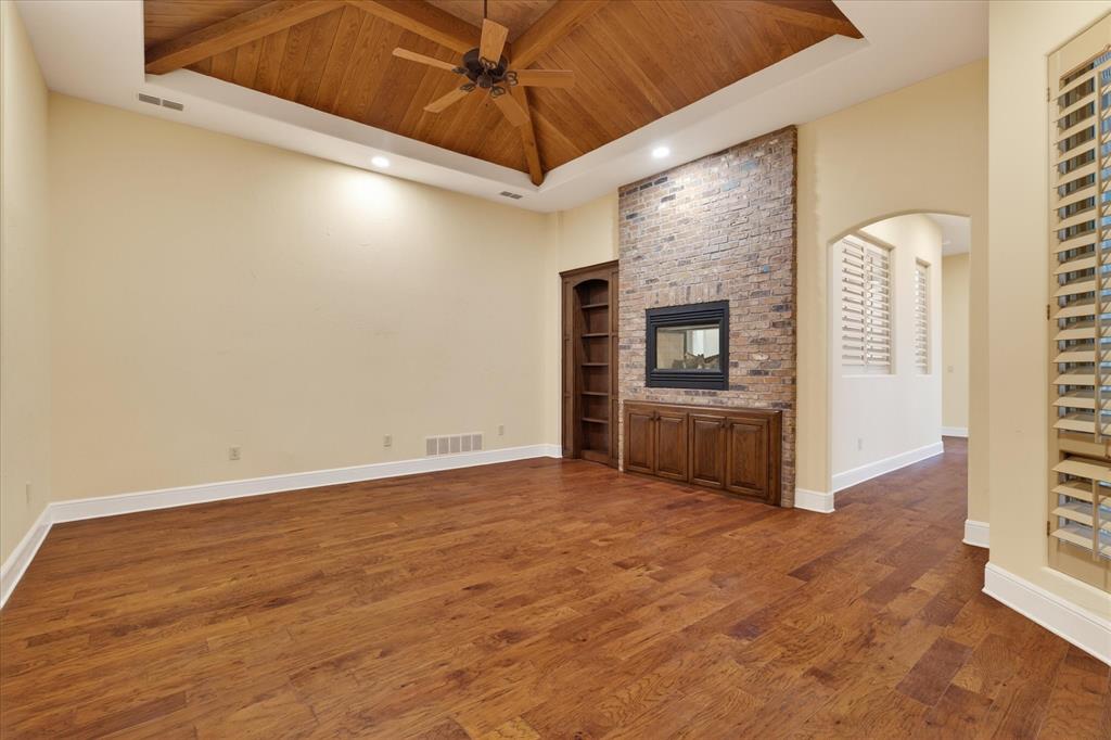 701 West Walcott Street Pilot Point, TX 76258 - Photo 23 of 40 Unfurnished living room with wooden ceiling, built in features, a brick fireplace, dark wood-type flooring, and recessed lighting
