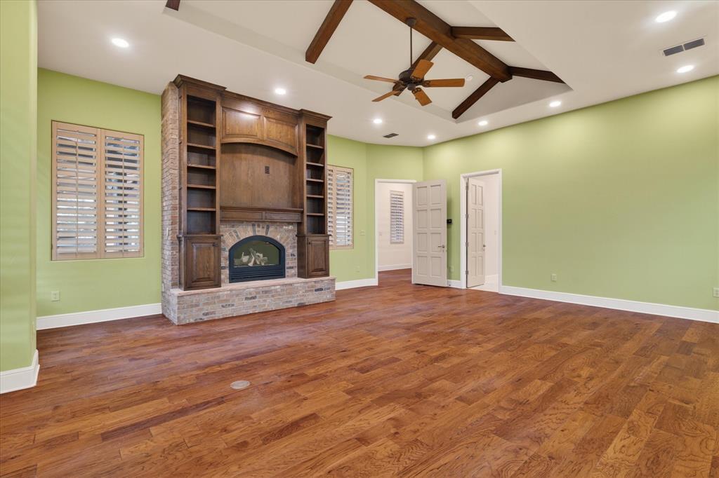 701 West Walcott Street Pilot Point, TX 76258 - Photo 24 of 40 Unfurnished living room featuring a fireplace, a ceiling fan, dark wood finished floors, recessed lighting, and vaulted ceiling with beams