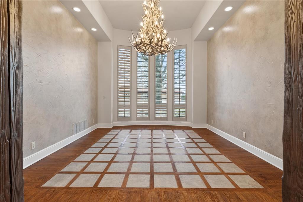 701 West Walcott Street Pilot Point, TX 76258 - Photo 29 of 40 Empty room featuring a chandelier, light wood-style flooring, and a textured wall