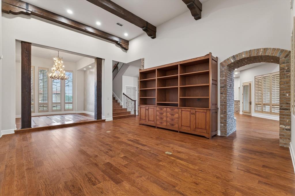 701 West Walcott Street Pilot Point, TX 76258 - Photo 31 of 40 Unfurnished living room with arched walkways, dark wood-type flooring, suspended lighting, and beamed ceiling