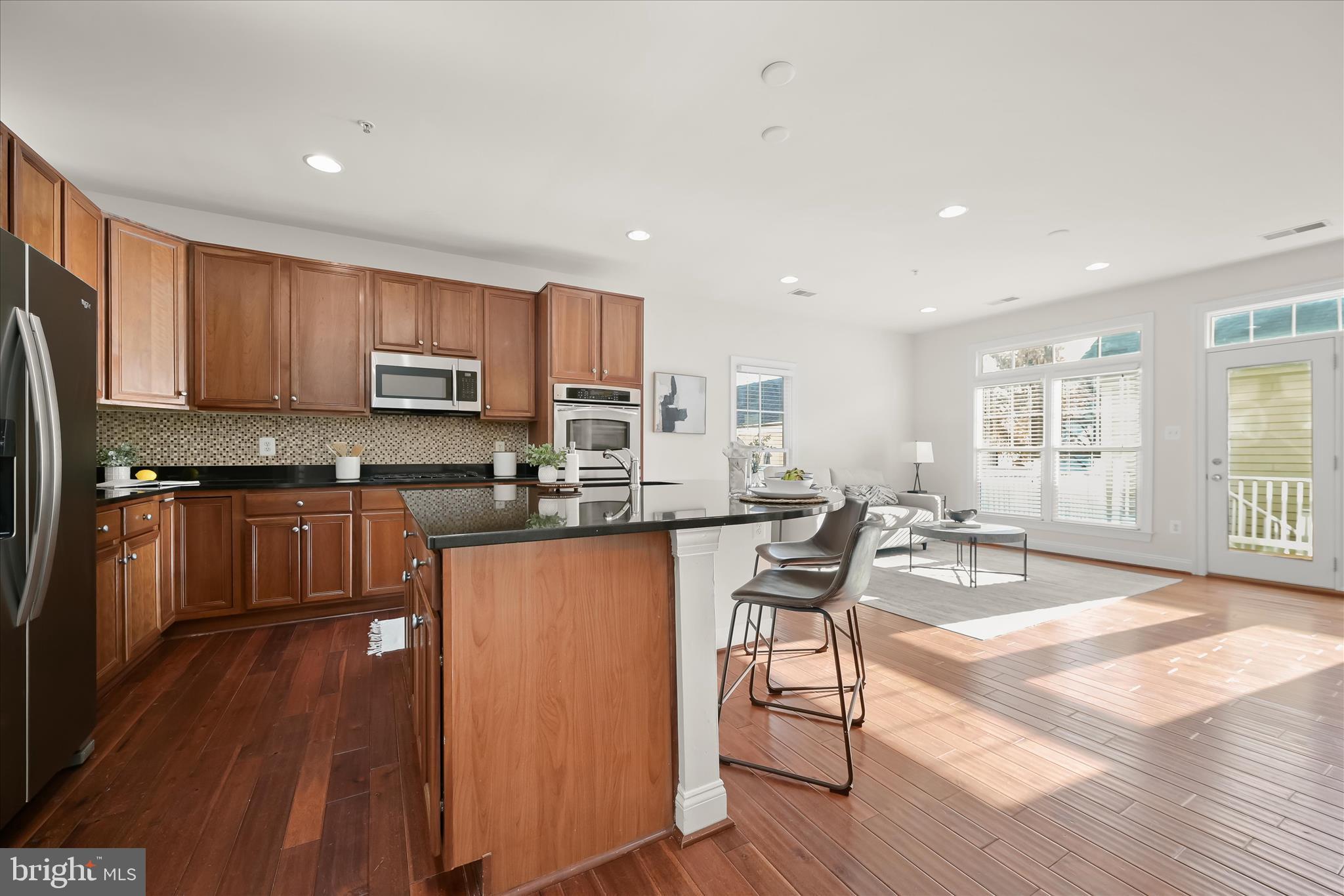 11419 Iager Boulevard Fulton, MD 20759 - Photo 7 of 58 a kitchen with stainless steel appliances granite countertop a stove top oven a sink dishwasher a dining table and chairs with wooden floor