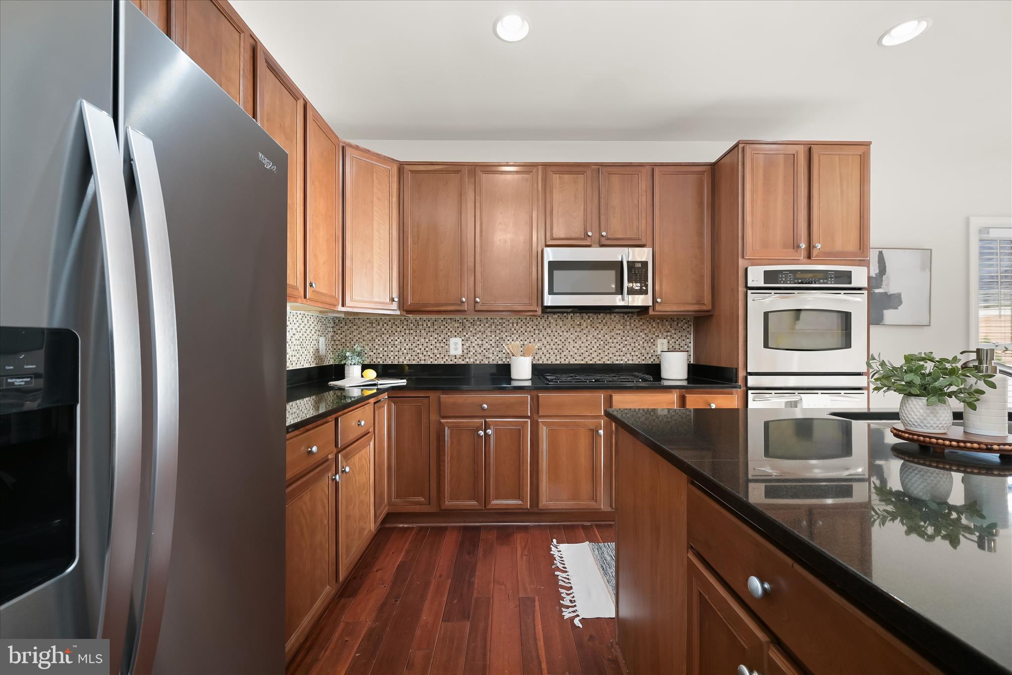 11419 Iager Boulevard Fulton, MD 20759 - Photo 9 of 58 a kitchen with stainless steel appliances granite countertop a refrigerator a stove top oven a sink and dishwasher with wooden floor