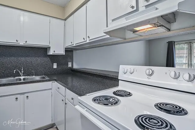 a kitchen with a sink a stove and cabinets