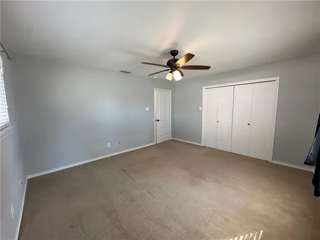 an empty room with a chandelier fan and windows