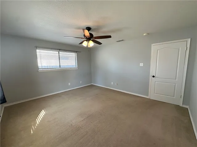 an empty room with windows and fan