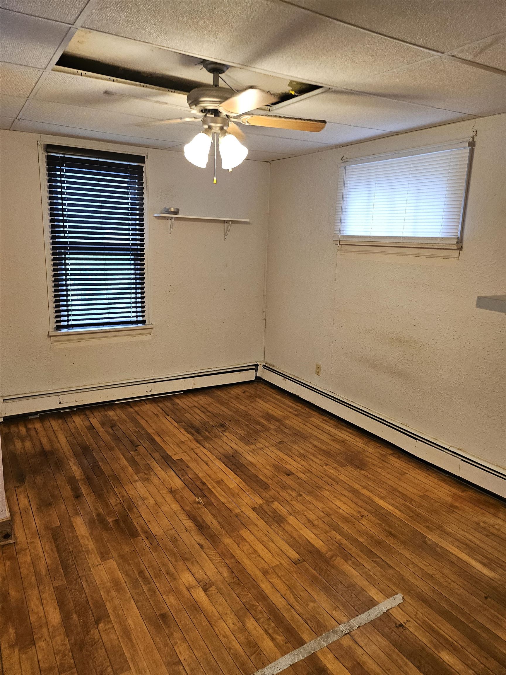 917 East 7th Street Duluth, MN 55805 - Photo 17 of 17 Empty room featuring baseboard heating, dark wood-type flooring, and ceiling fan