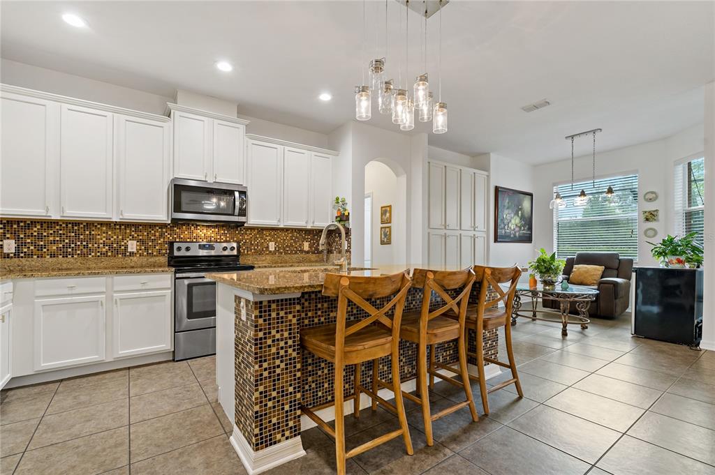 178 Magneta Loop Auburndale, FL 33823 - Photo 11 of 77 a kitchen with stainless steel appliances kitchen island granite countertop a refrigerator a stove a sink a dining table and chairs with white cabinets
