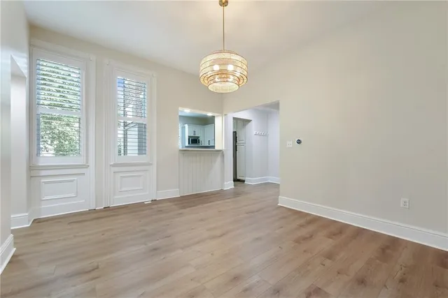 a view of an empty room with a window and wooden floor