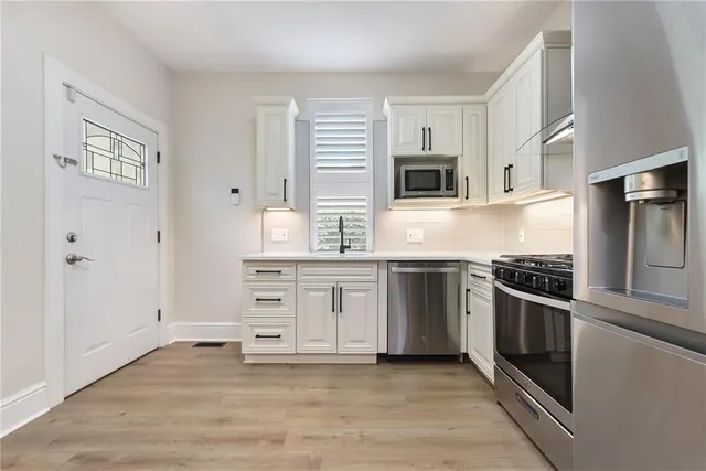 a kitchen with stainless steel appliances white cabinets and a stove top oven