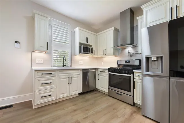 a kitchen with cabinets stainless steel appliances a sink and a window