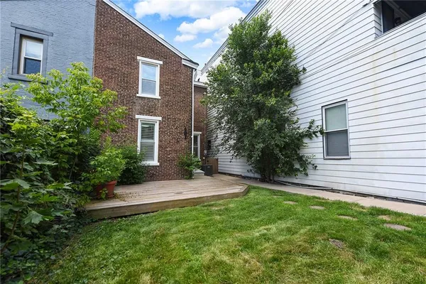 a view of a brick house with a yard and plants