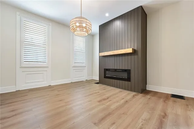 an empty room with wooden floor fireplace and window