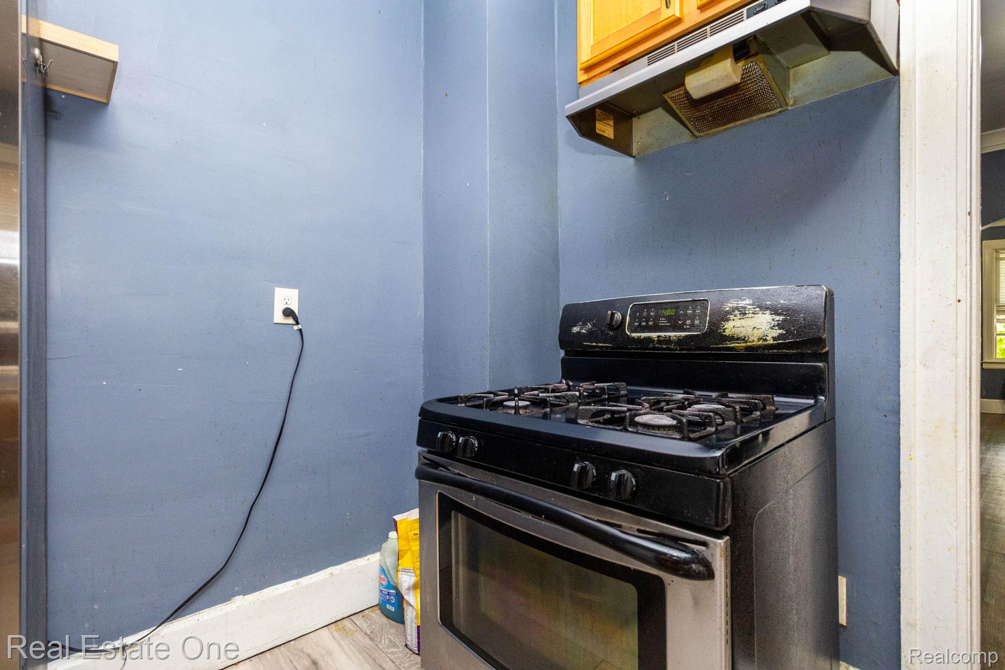 5485 Springwells Street Detroit, MI 48210 - Photo 21 of 47 Stainless steel and black gas range with an overhead vent and light wood-finish cabinetry