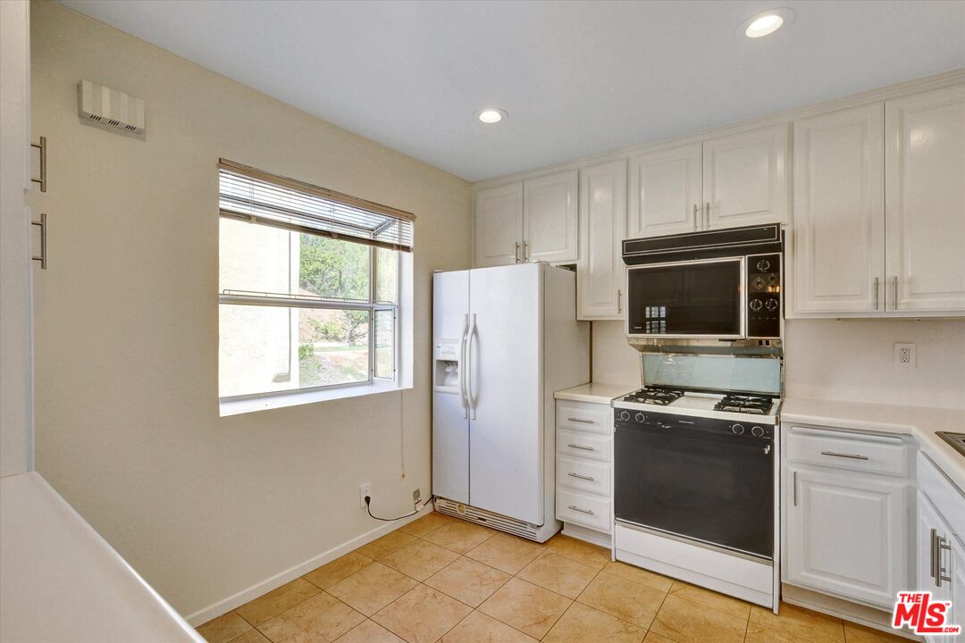 9634 Via Rimini, Unit 118 Sun Valley, CA 91504 - Photo 10 of 33 a kitchen with stainless steel appliances a refrigerator stove and microwave