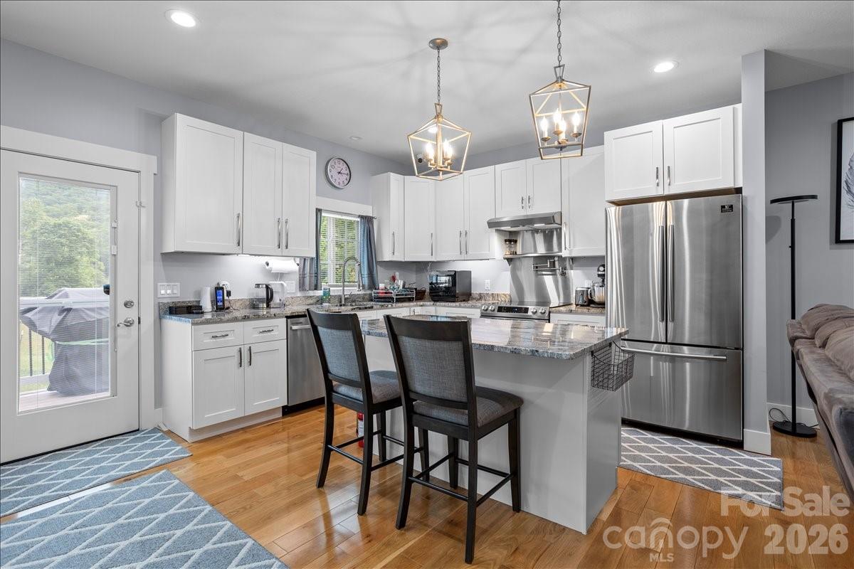 24 Mink Farm Road Leicester, NC 28748 - Photo 11 of 35 a kitchen with stainless steel appliances granite countertop a refrigerator a sink dishwasher a stove a dining table and chairs with wooden floor