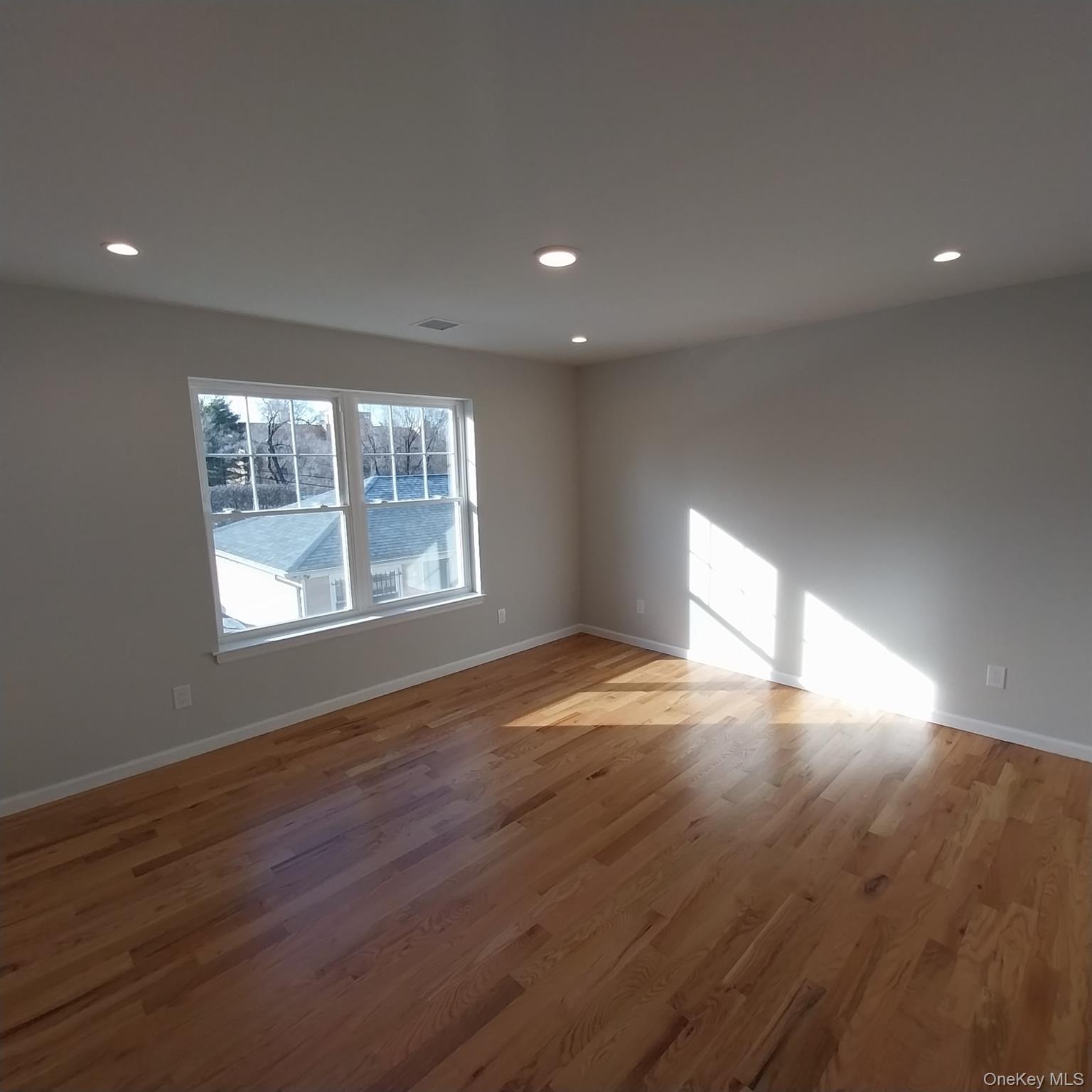 343 Jackson Street, Unit 3 Hempstead, NY 11550 - Photo 18 of 23 a view of an empty room with wooden floor and a window