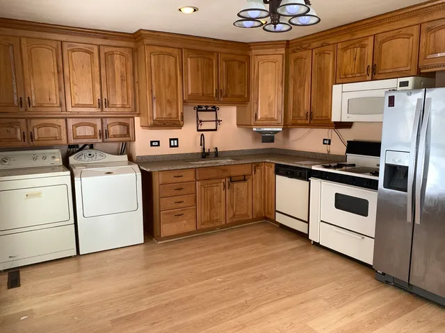 a kitchen with a stove white refrigerator sink and cabinets