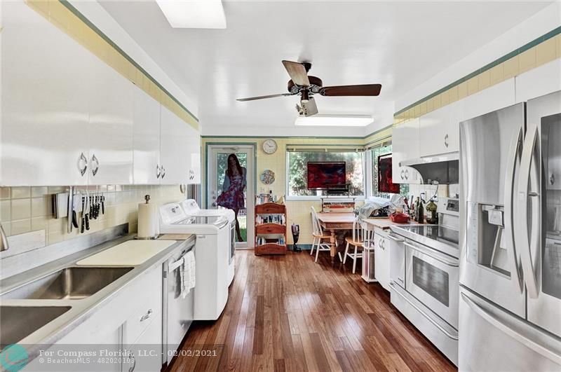 2102 Bay Drive Pompano Beach, FL 33062 - Photo 14 of 71 a kitchen with stainless steel appliances kitchen island granite countertop a refrigerator a stove a sink dishwasher and white cabinets with wooden floor