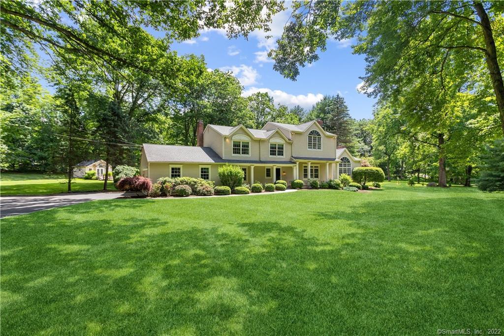 a view of a house with a big yard and large trees
