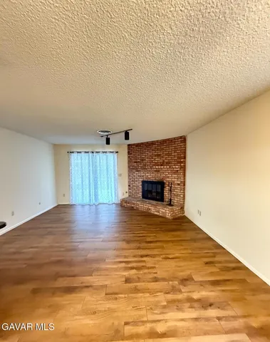 a view of empty room with wooden floor and fireplace