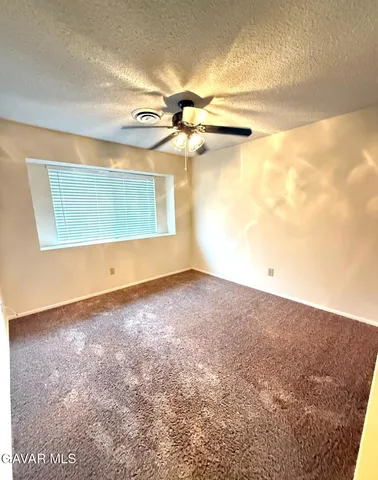 en empty room with windows and ceiling fan