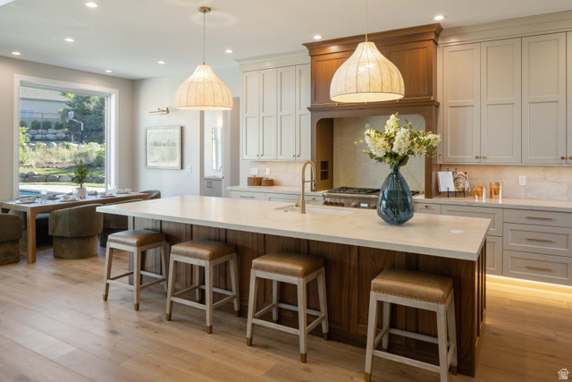 4292 Silver Sage Circle Alpine, UT 84004 - Photo 9 of 41 Spacious kitchen featuring a large central island with seating, pendant lighting, wood-finish flooring, light-toned cabinetry, and a built-in range hood