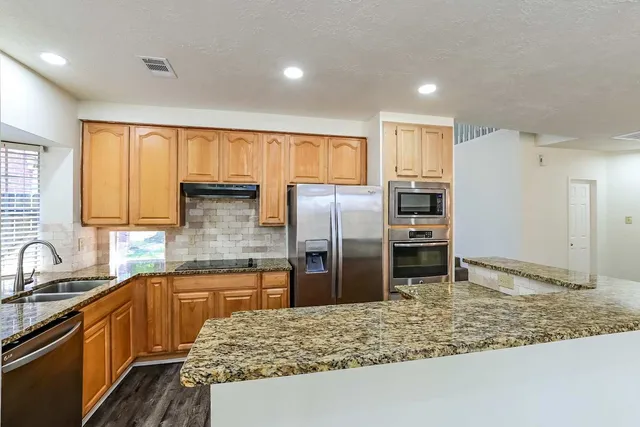 a kitchen with stainless steel appliances granite countertop a refrigerator and a sink
