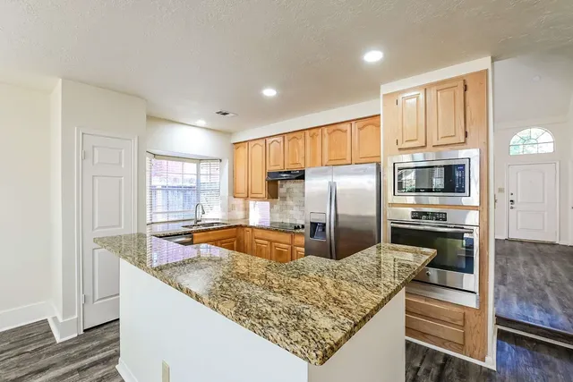 a kitchen with stainless steel appliances granite countertop a refrigerator a stove and a sink