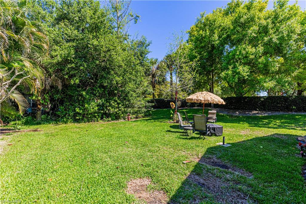 1364 Triandra Lane Naples, FL 34119 - Photo 2 of 27 a view of a garden with a bench and some trees