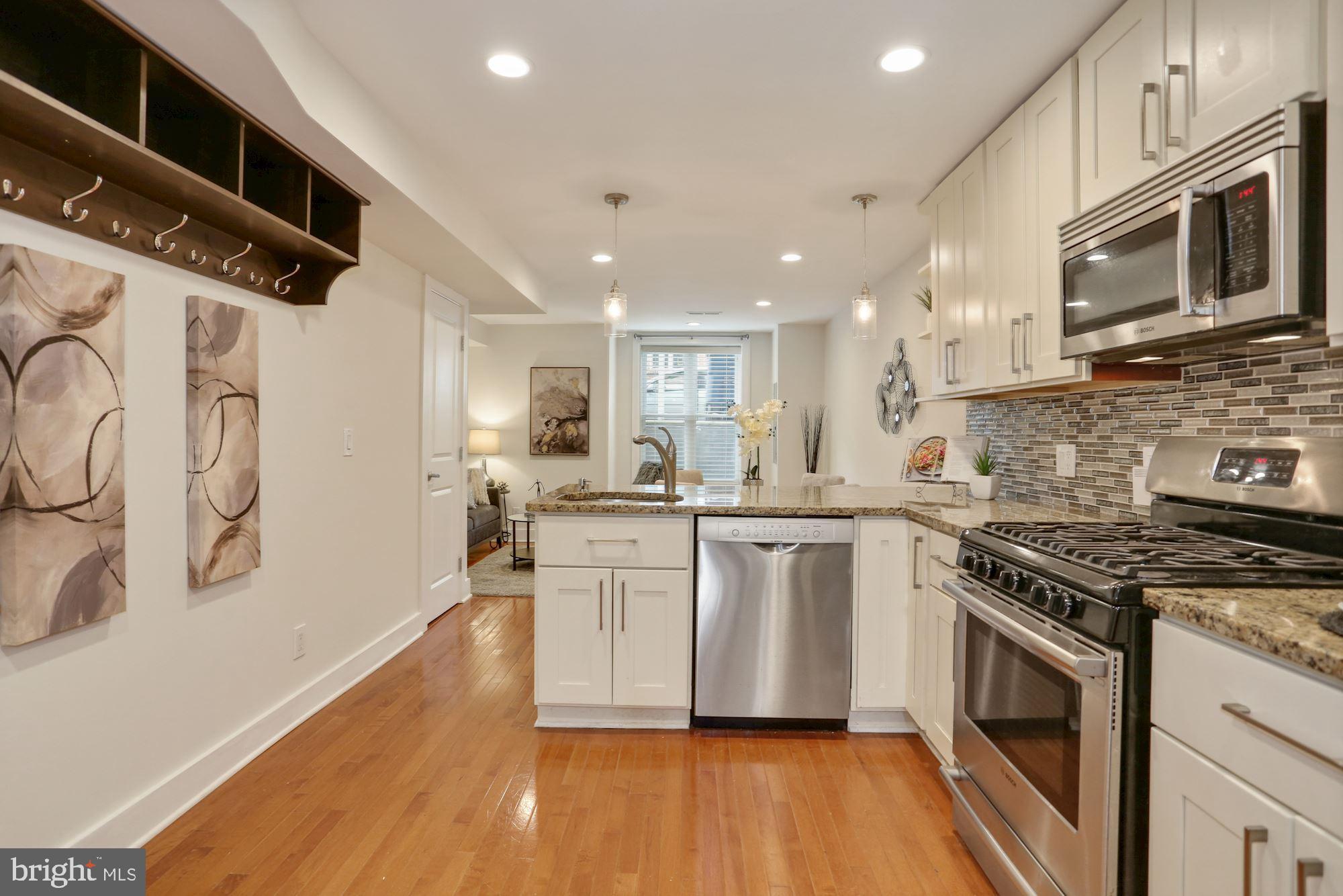43 Hanover Place Northwest, Unit 1 Washington, DC 20001 - Photo 2 of 23 a kitchen with stainless steel appliances granite countertop a stove top oven a sink a refrigerator white cabinets and wooden floor