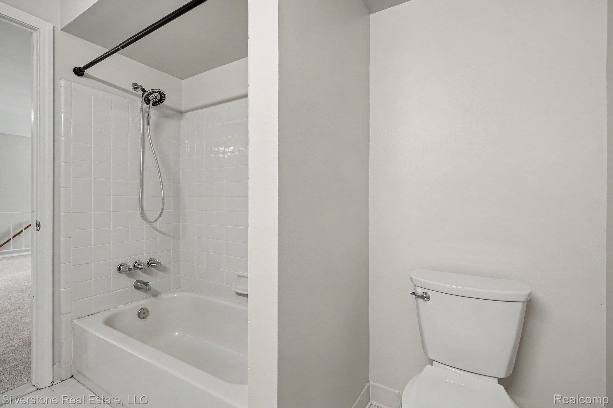 1502 Meadowside Drive Rochester, MI 48307 - Photo 22 of 27 White tiled shower and tub combination featuring chrome fixtures and a handheld showerhead