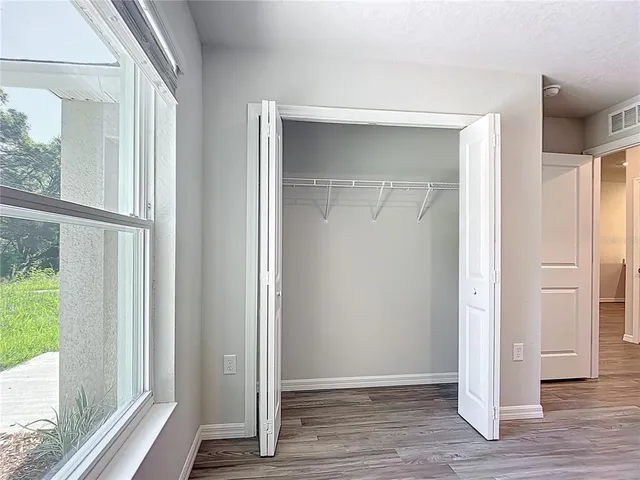 a view of an empty room with wooden floor and windows