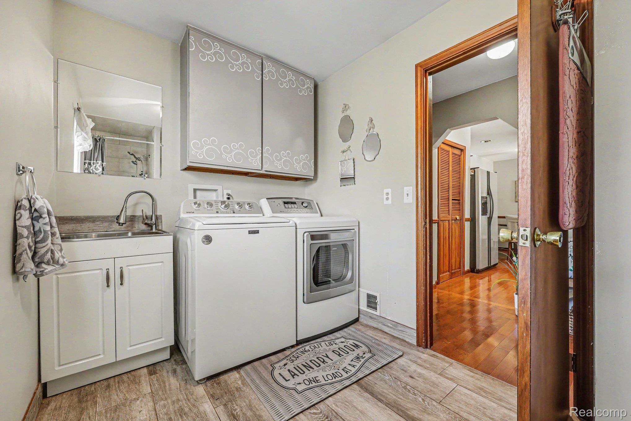 7020 Meldrum Road Fair Haven, MI 48023 - Photo 26 of 43 Dedicated laundry area featuring wood-finish flooring, white cabinetry with a built-in sink, and upper storage cabinets