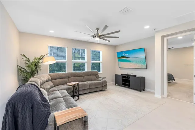 a living room with furniture a flat screen tv and a large window