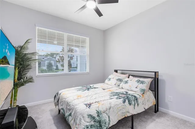 a bed sitting in a bedroom next to a window and a chair