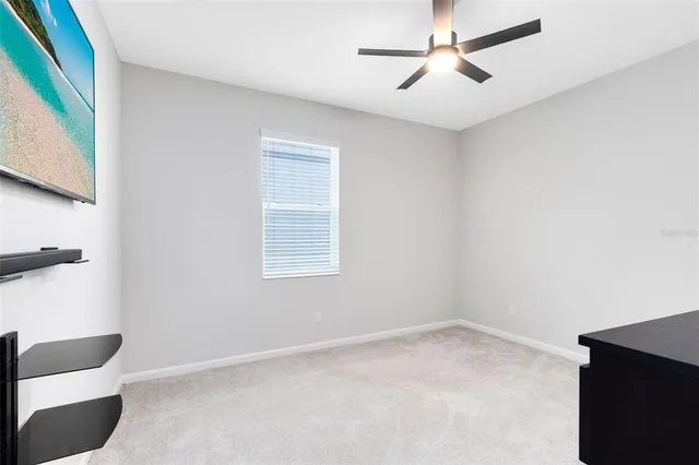a view of an empty room with a ceiling fan and a window