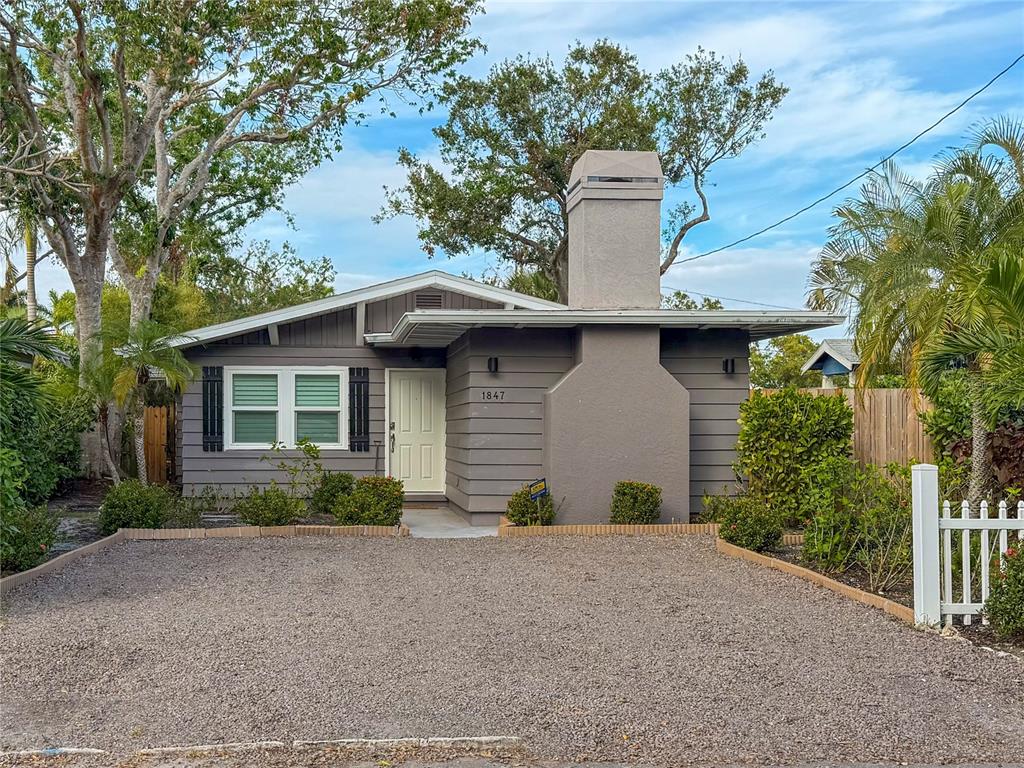 a view of a house with a yard plants and large tree