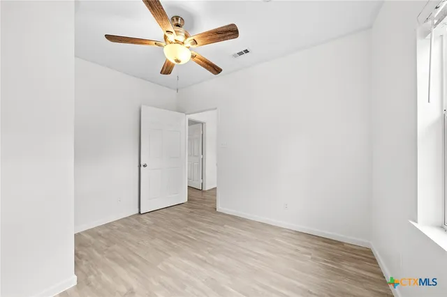 a view of a room with wooden floor and a ceiling fan