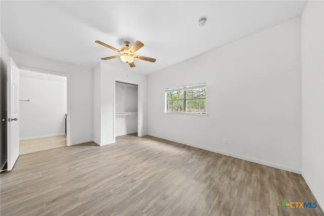 an empty room with a window and a ceiling fan