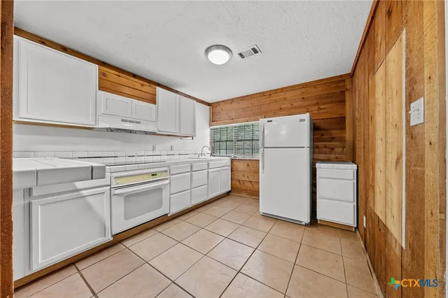a kitchen with a refrigerator a stove top oven and cabinets