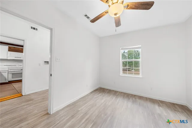 an empty room with wooden floor cabinet and windows
