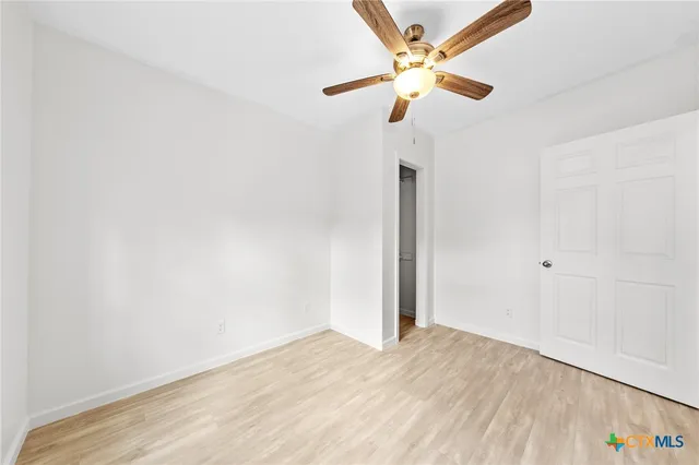 an empty room with a window and a ceiling fan