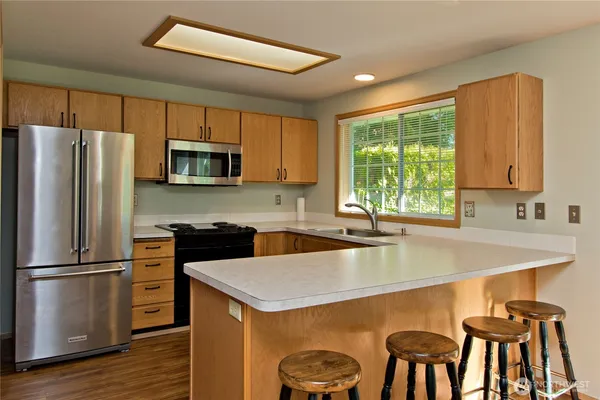 a kitchen with kitchen island a stove a sink a microwave and refrigerator