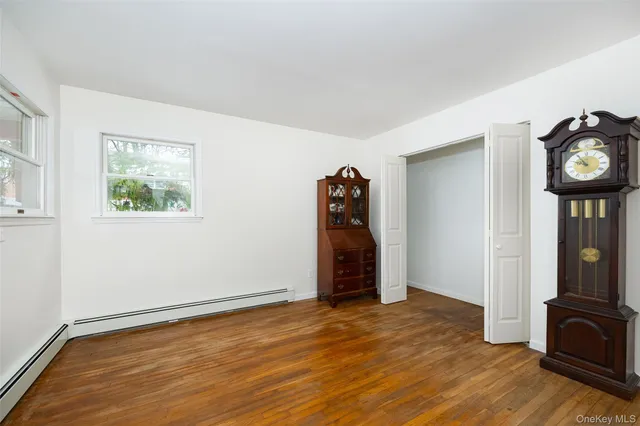 an empty room with wooden floor closet and windows